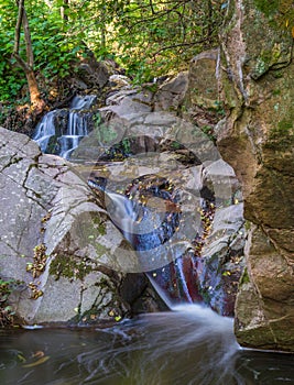 Small waterfall between rocks in autumn