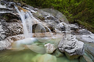 A small waterfall runs over white rock and into an emeral pool