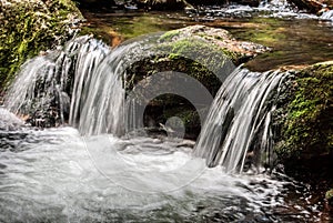 Small waterfall with stone covered by moss