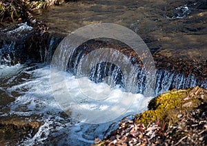 Small waterfall on stream with flowing water