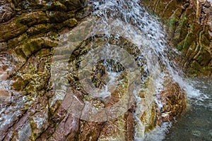 Small waterfall on a textured stone wall on the river Krikiliotis at Panta Vrexei in Evritania, Greece