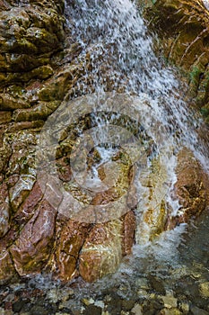 Small waterfall on a textured stone wall on the river Krikiliotis at Panta Vrexei in Evritania, Greece