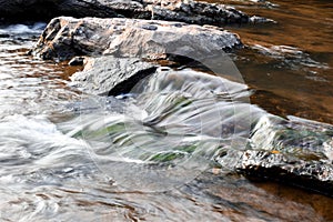 Small waterfall timelapse from rocks smooth waterfall black brown in forest ripples and flow