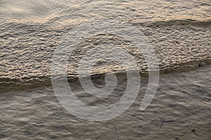 a small wave on the beach in sunset