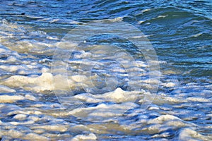 Small wave on the ocean shore, foam forms on the wave, close-up shot