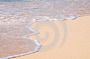 A small wave rolls up the white sand beach on the tropical island of Grand Turk