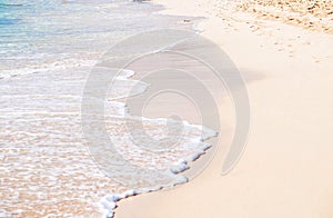 A small wave rolls up the white sand beach on the tropical island of Grand Turk