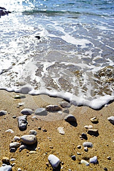 A small wave on the sand and pebble beach.