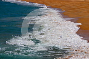 Small waves breaking on the sand of NazarÃ© Beach, Portugal. photo