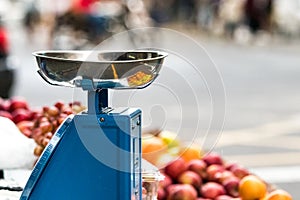 A small weight scale in a aoutdoors vegetables market over a fruits blurred background in Mauritius