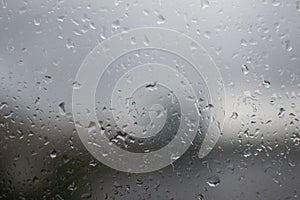 Small wet raindrops on window glass. Damp rainy sad weather. Blurry outline Ñity outside