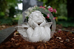 Small white angel figure lying on a grave