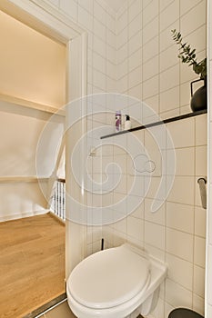 a small white bathroom with a toilet and a staircase