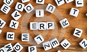 Small white and black bead cubes on wooden board, letters in middle spell ERP - Enterprise resource planning concept