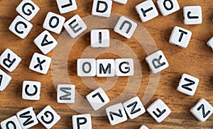 Small white and black bead cubes on wooden board, letters in middle spell OMG