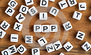 Small white and black bead cubes on wooden board, letters in middle spell PPP - Praise, Picture, Push concept