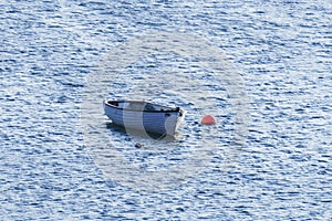 Small white boat attached to a red buoy in Olshoremore, Scotland