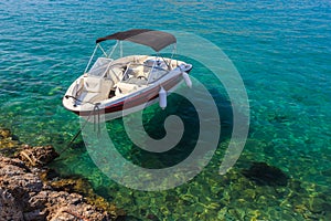 Small white boat floating in clean water near shore