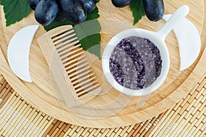 Small white bowl with homemade grape and sugar body scrub bath salt, foot soak and wooden hairbrush. Natural beauty treatment an