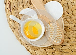 Small white bowl with raw egg and wooden hairbrush. Natural skin and hair care, homemade spa and beauty treatment recipe. Zero