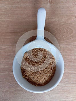 Small White Bowl With Stick Filled With Brown Crystallized Sugar