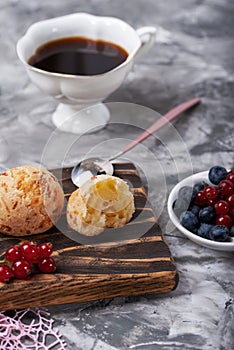 Small white buns with fresh berries with cup of coffee on a concrete texture background