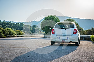 Small white car with led optics on the asphalt road highway