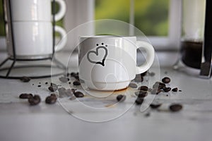 Small white ceramic espresso cup with heart drawn on it scattered coffee beans