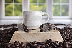 Small white ceramic espresso cup sitting on a pile of coffee beans