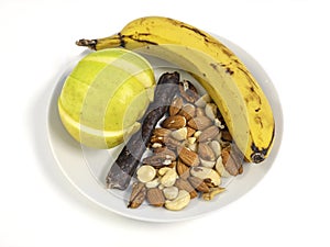 Small white ceramic plate with fresh healthy snacks banana apple nuts biltong droewors