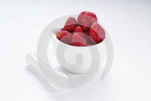 Small white china bowl filled with succulent juicy fresh ripe red strawberries