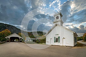 Small white church building and covered bridge in the village of Stark, New Hampshire.