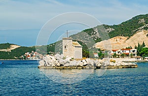 Small white church on the island in Klek, Adriatic sea and high mountains in the background