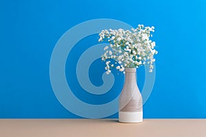 Small white flowers on a blue background. Soft home decor. Gypsophila flowers. White flowers in a vase. Retro style