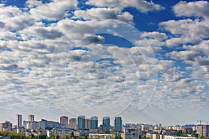 Small white-gray clouds gradually obscure the blue sky above the city