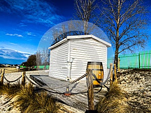 Small white house on the beach with retro well and wooden barrel