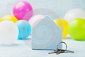 Small white house with bunch of keys and air balloons. Housewarming, moving, real estate or buying a new home concept.