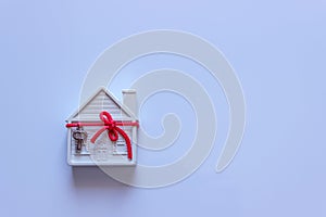 A small white house is decorated with a decorative key on a red ribbon.