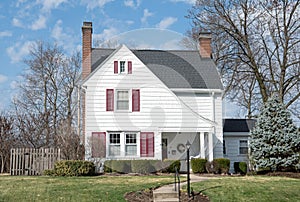 Small White House with Sloping Roofline and Red Shutters photo