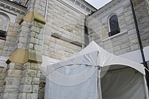 Small white information or events tent against stone walls