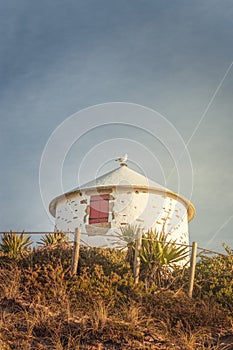 A small, white lighthouse tower sitting on top of a hill