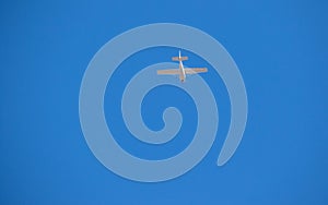 Small white plane flies in the blue sky
