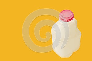 A small white plastic milk canister with a red lid on a yellow background