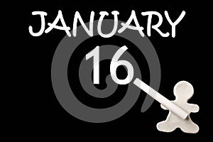 A small white plasticine man writing the date 16 January on a black board. Business concept. Education concept.