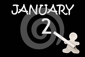 A small white plasticine man writing the date 2 January on a black board. Business concept. Education concept.