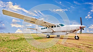 A small white private charter plane in an African landscape.