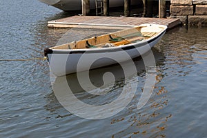 Small white rowboat moored by dock and stone wall