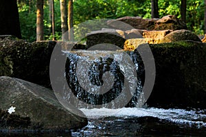 A small white-soft waterfall covering sharp structure of huge dark rocks