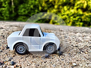 A small white toy car on the background of a natural landscape. The concept of travel and adventure by car. Freedom of