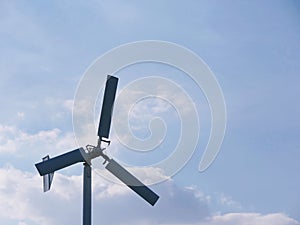 Small white wind turbine, windmill alternative Green clean energy against blue sky